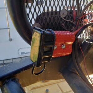 A red and black device hanging on the side of a fence.