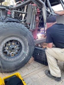 A man working on the tire of an off road vehicle.