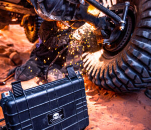 A person is welding in the dirt with an atv.